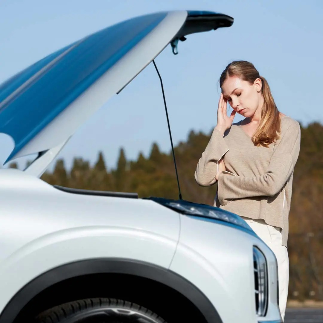 Driver beside a vehicle with its hood open